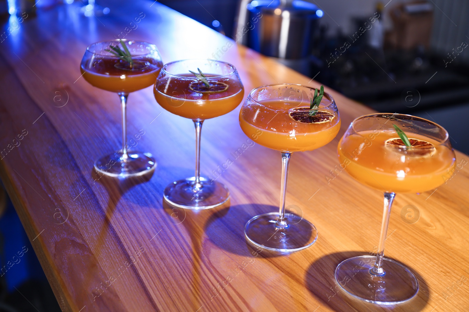 Photo of Glasses of delicious cocktail with vodka on wooden counter in bar