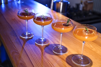 Photo of Glasses of delicious cocktail with vodka on wooden counter in bar