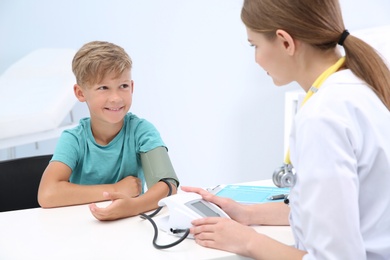 Doctor checking little boy's pulse in hospital