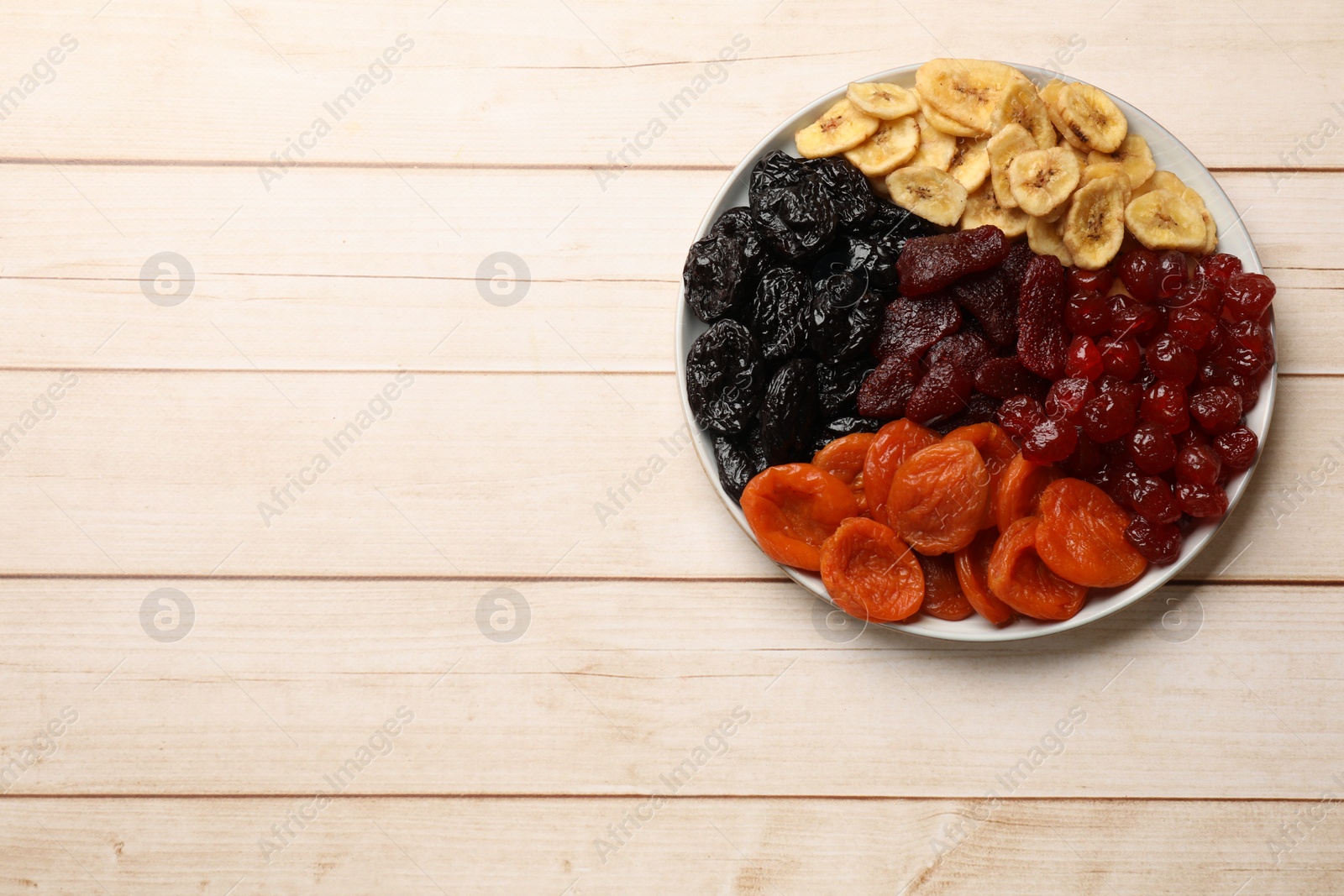 Photo of Delicious dried fruits on white wooden table, top view. Space for text