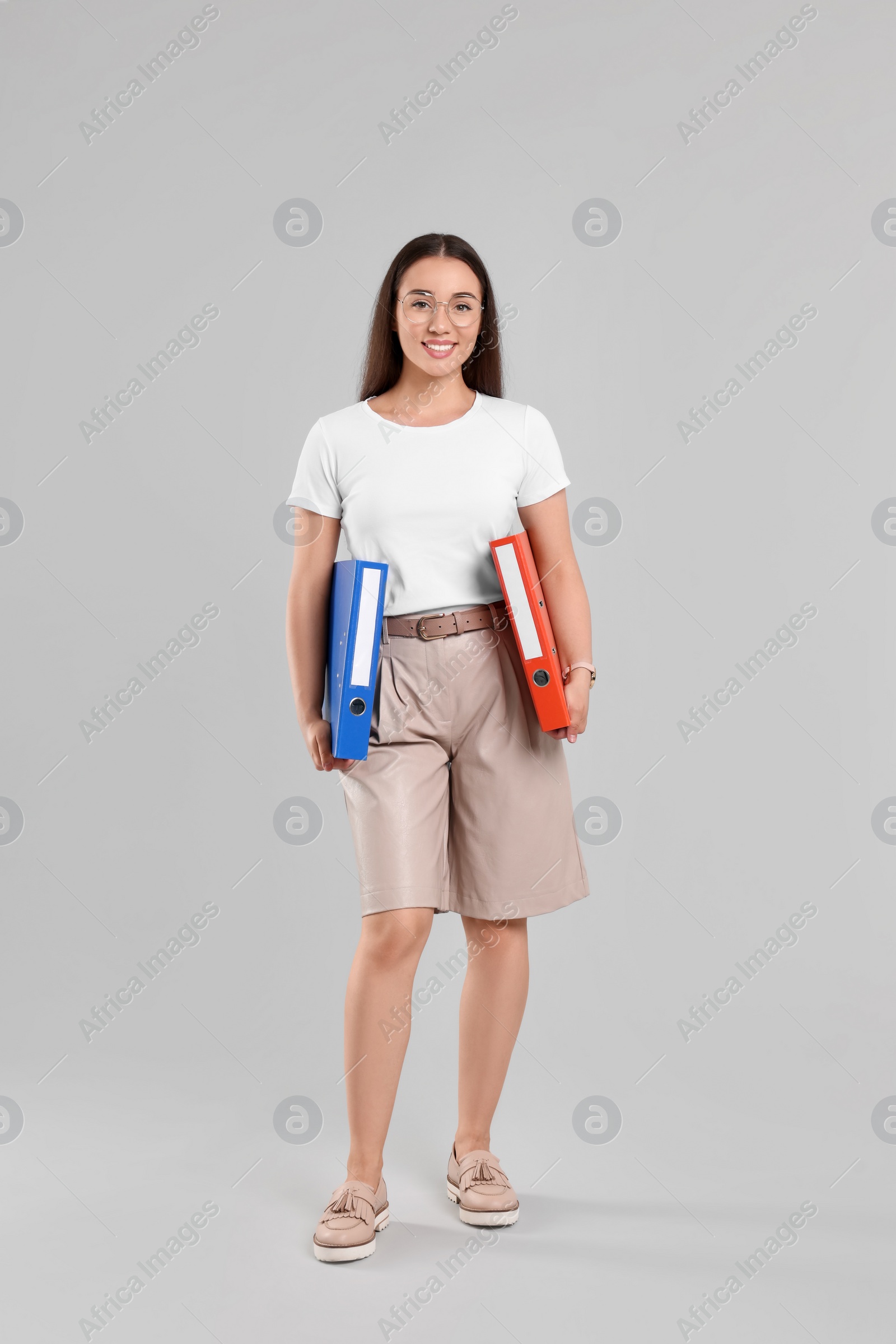 Photo of Happy woman with folders on light gray background