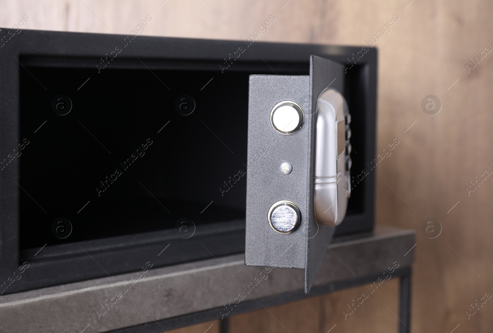 Photo of Black steel safe with electronic lock on grey table, closeup