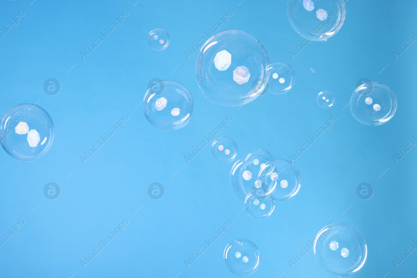 Photo of Many beautiful soap bubbles on light blue background