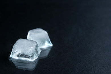 Photo of Ice cubes on black surface, closeup. Space for text