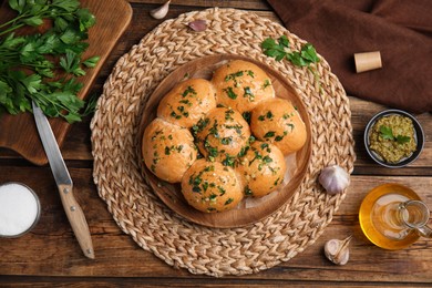 Photo of Traditional pampushka buns with garlic and herbs on wooden table, flat lay