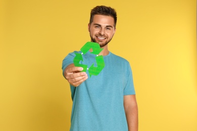 Young man with recycling symbol on yellow background