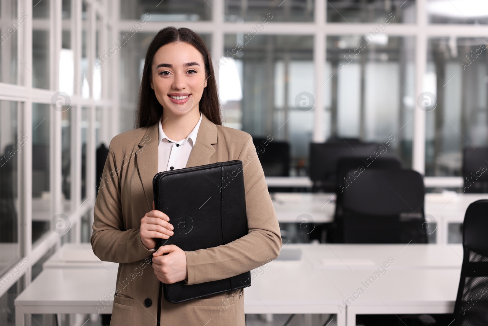 Photo of Happy real estate agent with leather portfolio indoors. Space for text