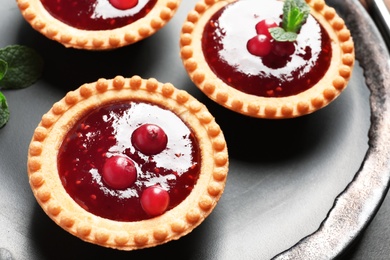 Tasty tartlets with jam on plate, closeup