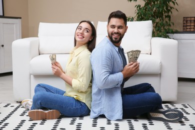 Photo of Happy couple with money on floor at home