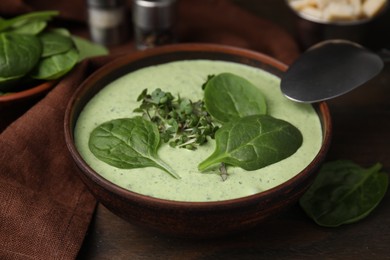 Delicious spinach cream soup served on wooden table, closeup