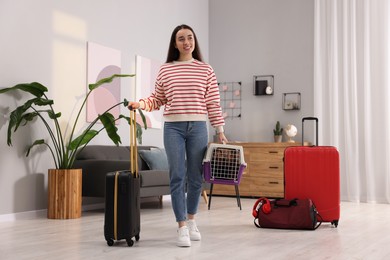 Travel with pet. Smiling woman holding carrier with dog and suitcase at home