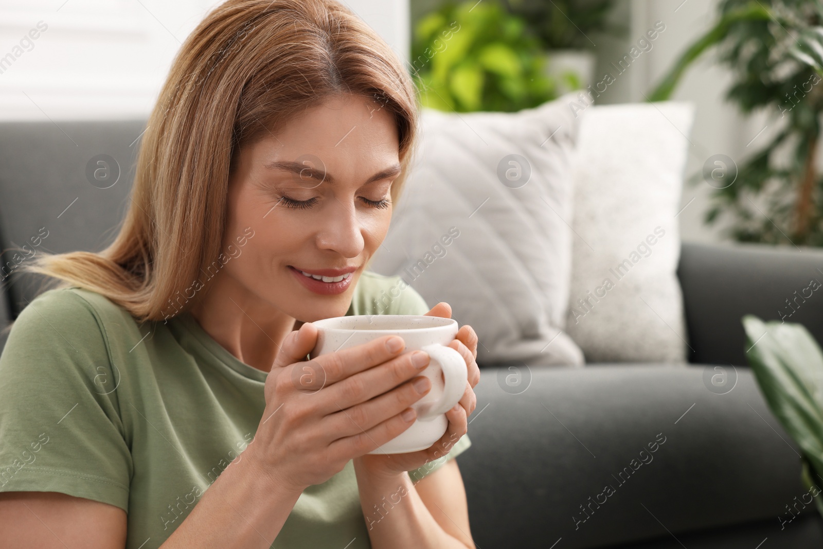 Photo of Woman holding cup of drink in room. Space for text