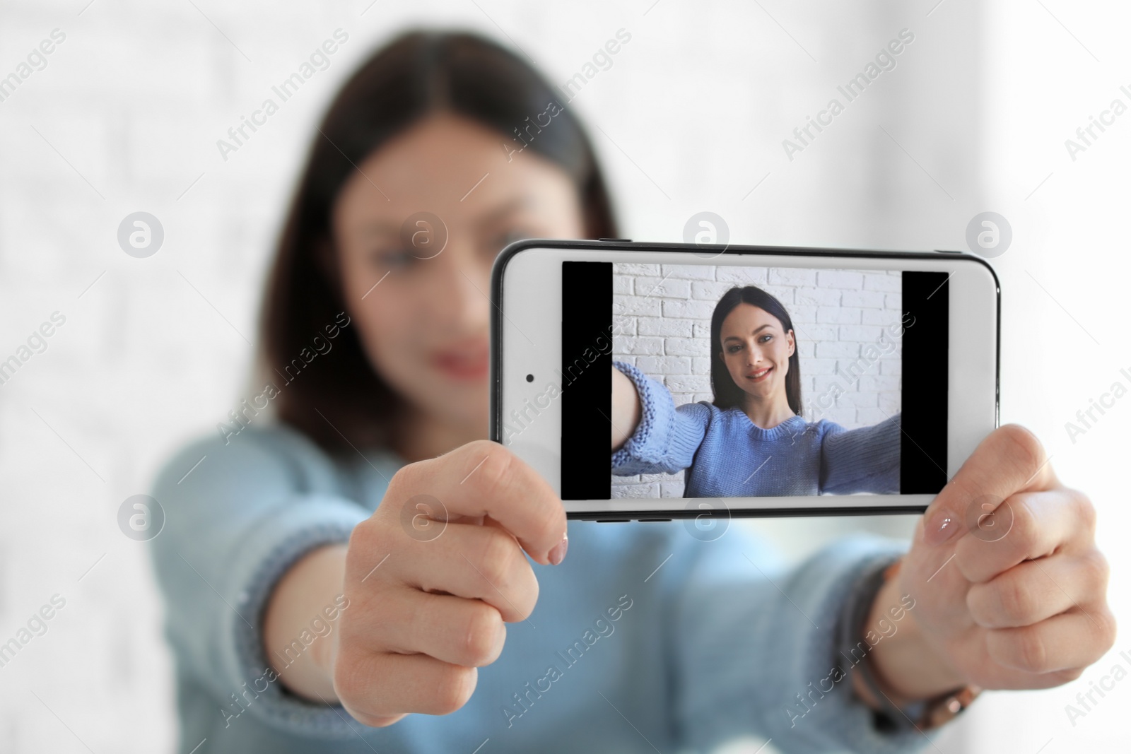 Photo of Attractive young woman taking selfie near brick wall, closeup