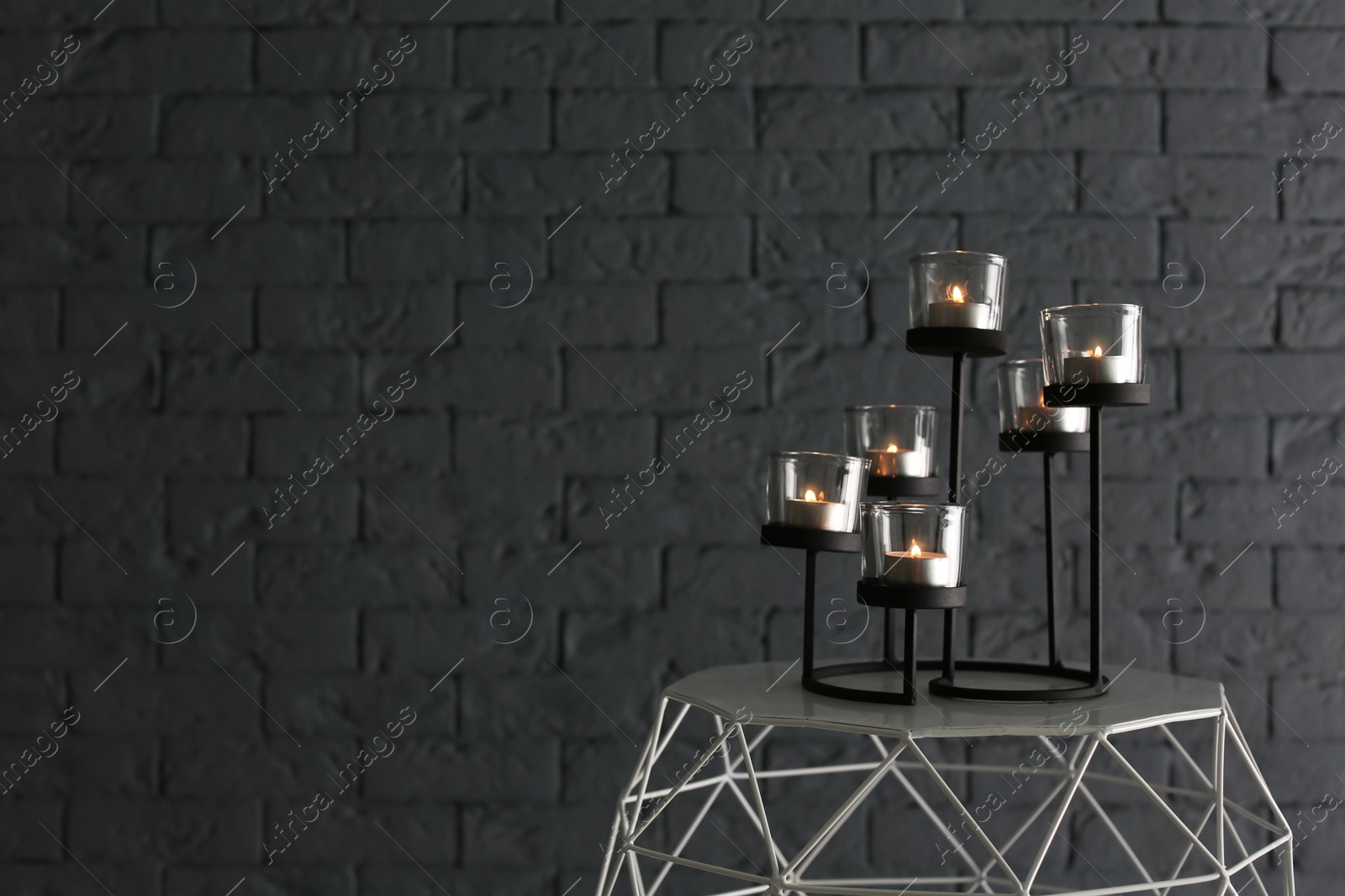 Photo of Burning candles on table near brick wall
