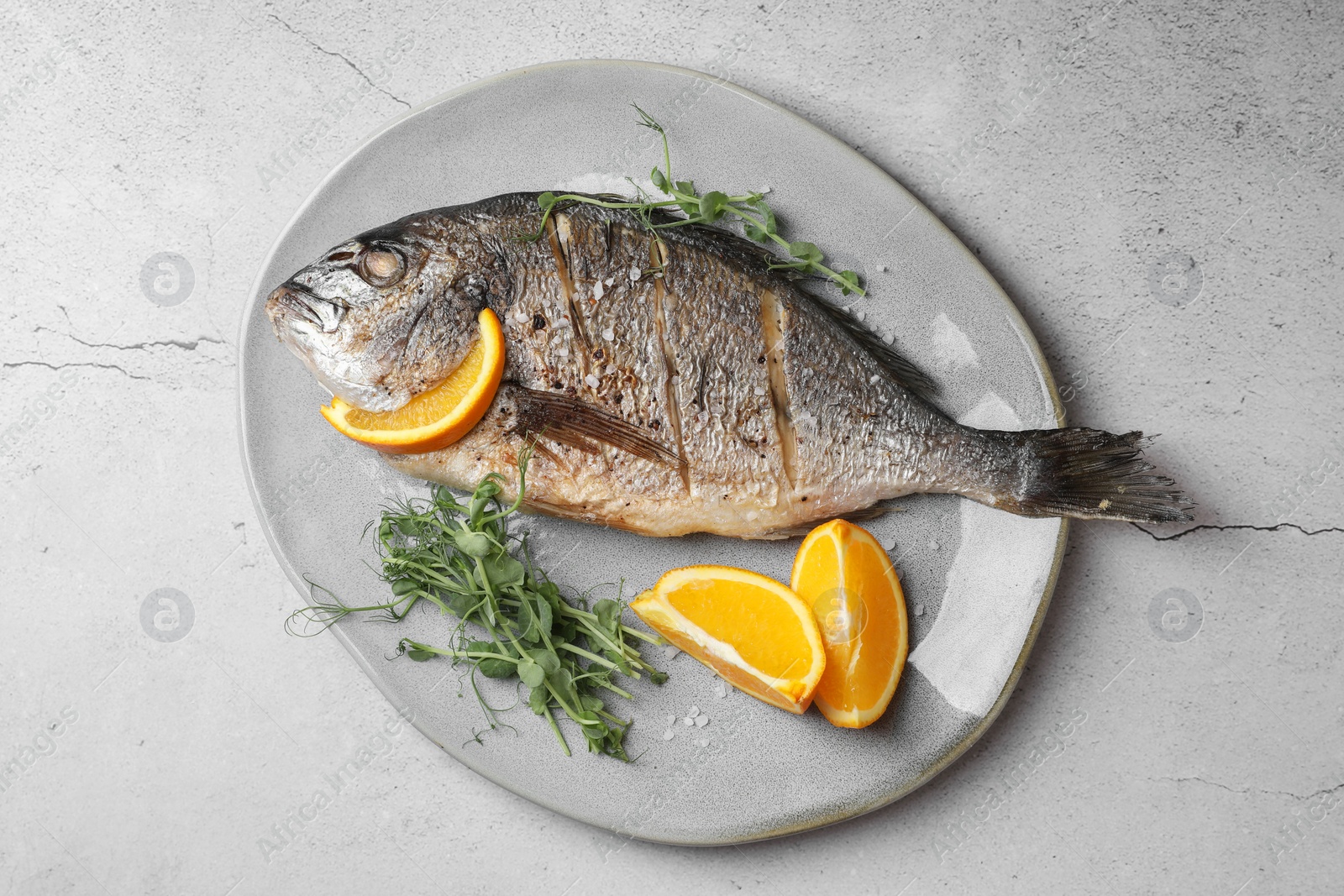 Photo of Seafood. Delicious baked fish served with orange and microgreens on light textured table, top view