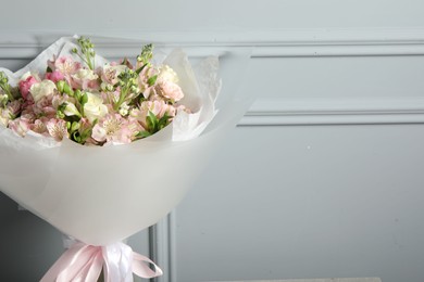 Photo of Beautiful bouquet of fresh flowers near grey wall, space for text