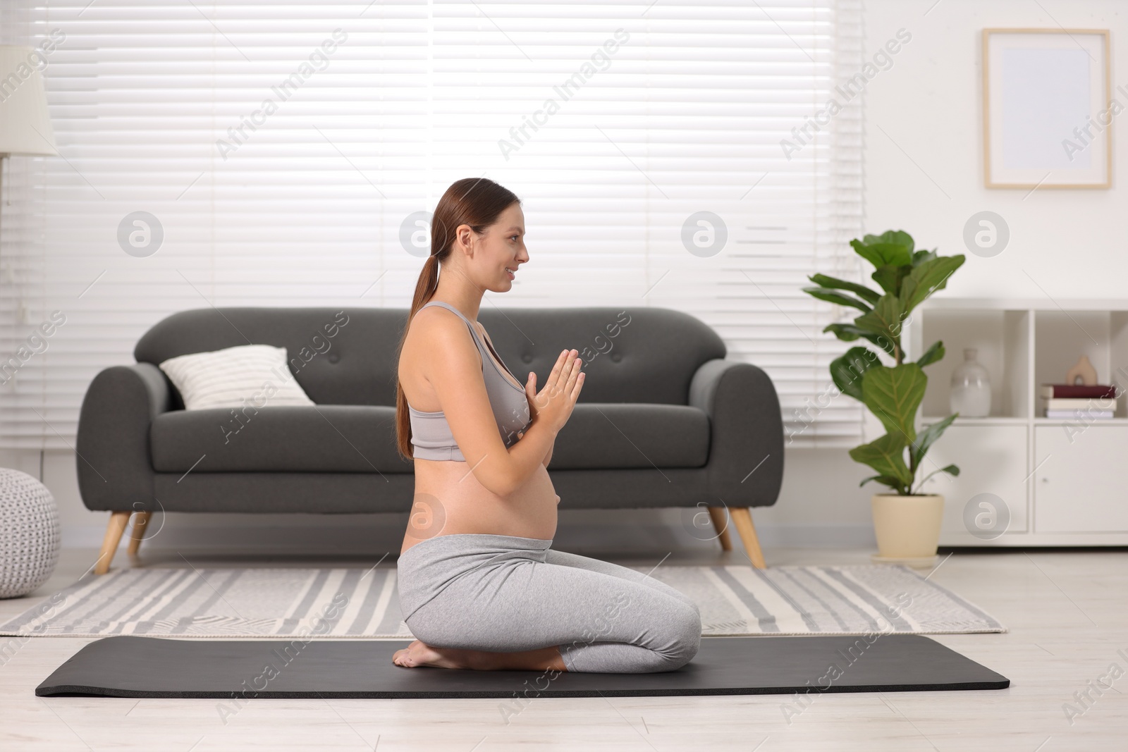 Photo of Pregnant woman meditating on yoga mat at home