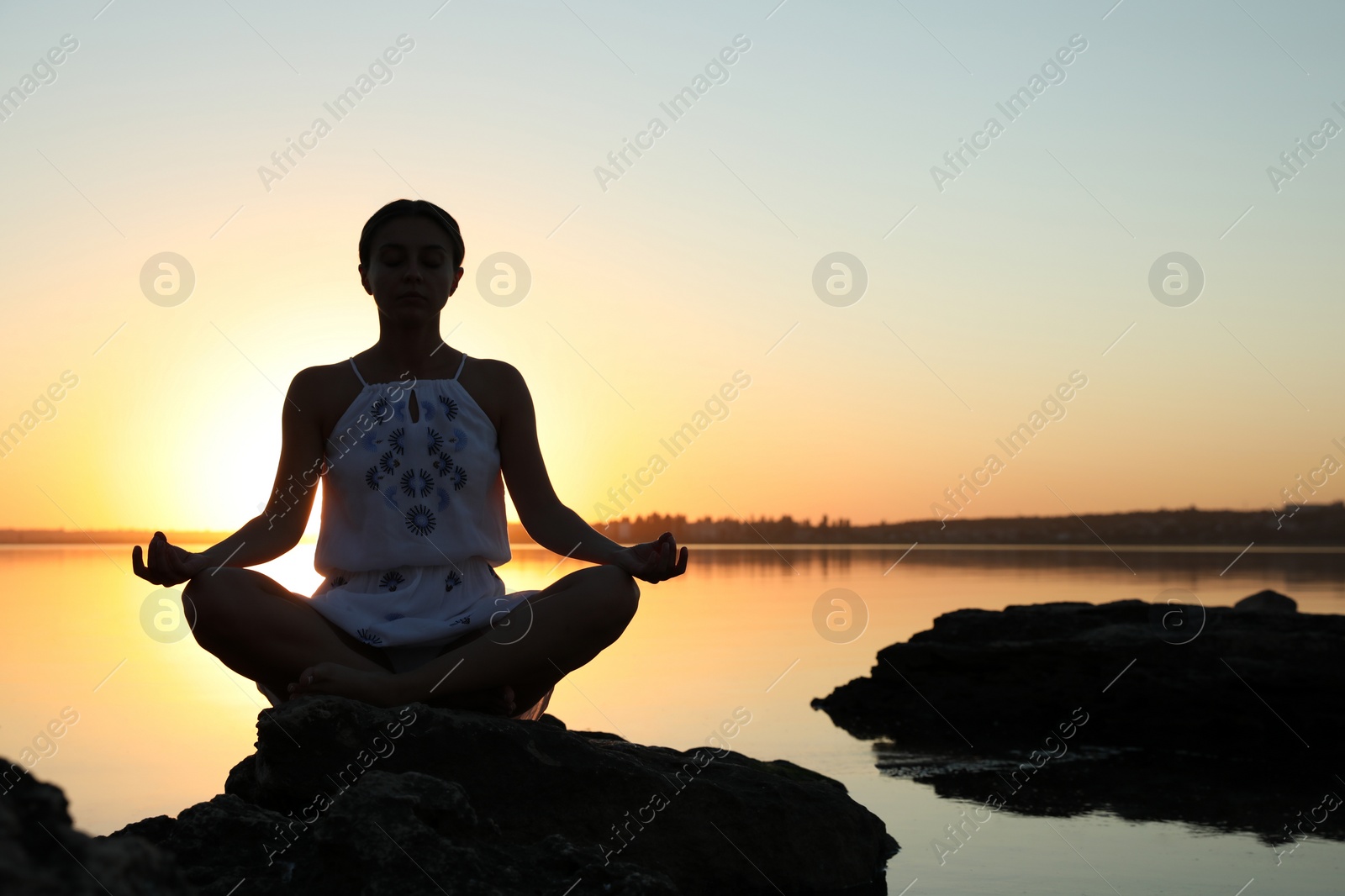 Photo of Woman practicing yoga near river on sunset. Healing concept