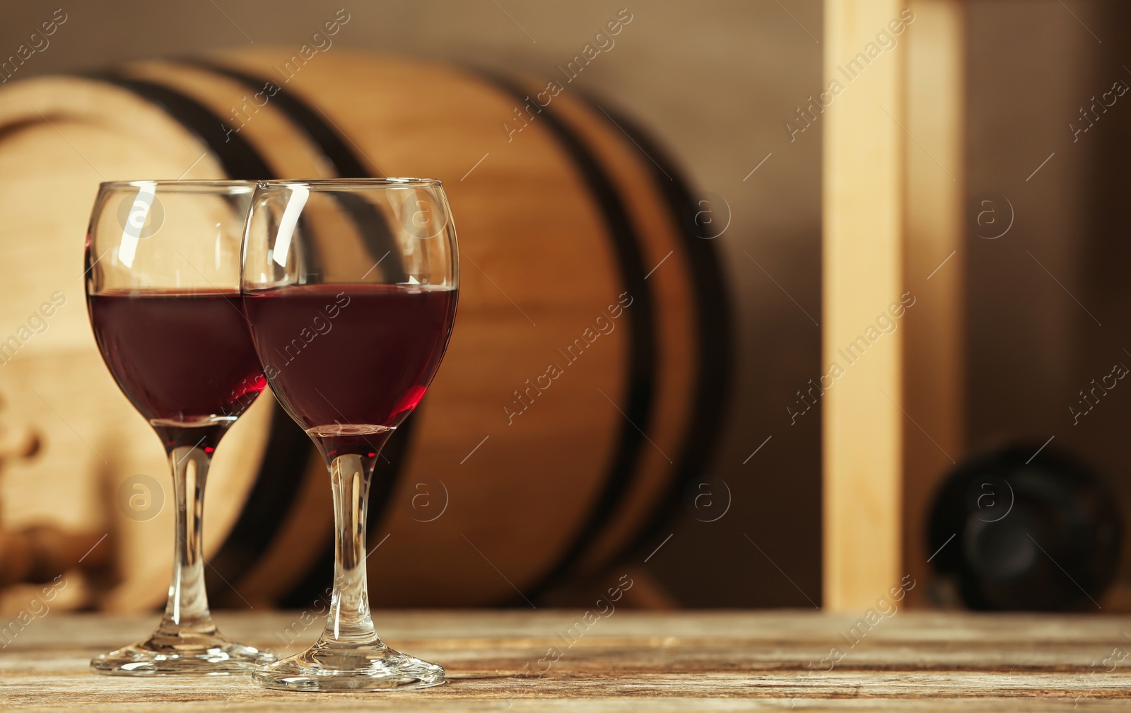 Photo of Glasses with red wine and blurred barrel on background