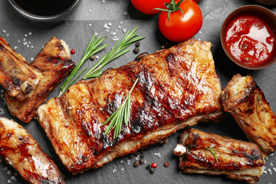 Photo of Delicious grilled ribs on black table, flat lay