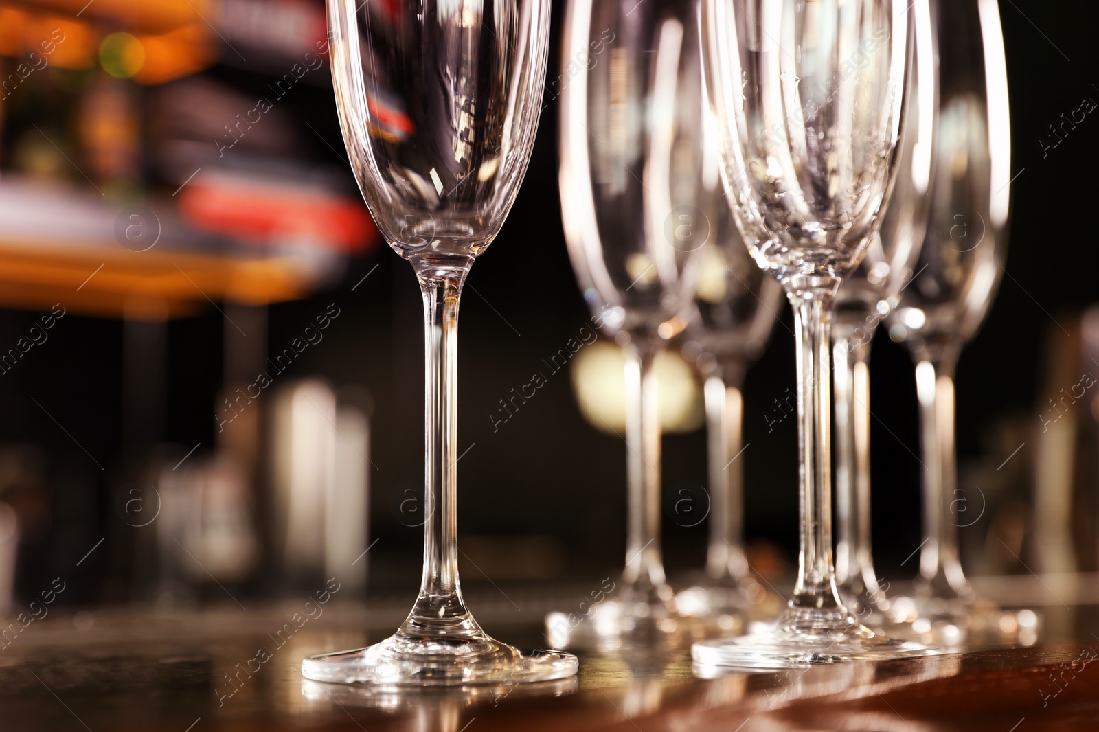 Photo of Empty clean champagne glasses on counter in bar, closeup