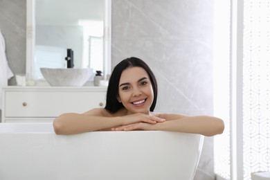 Photo of Beautiful young woman relaxing in bathtub at home