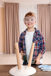 Boy in protective glasses repairing stool at home
