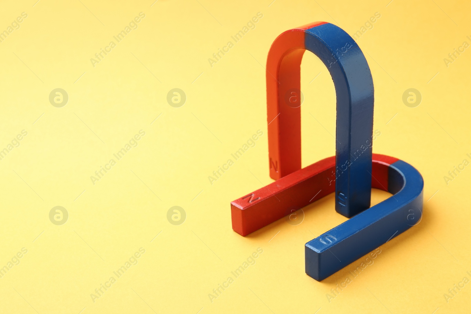 Photo of Red and blue horseshoe magnets on color background. Space for text