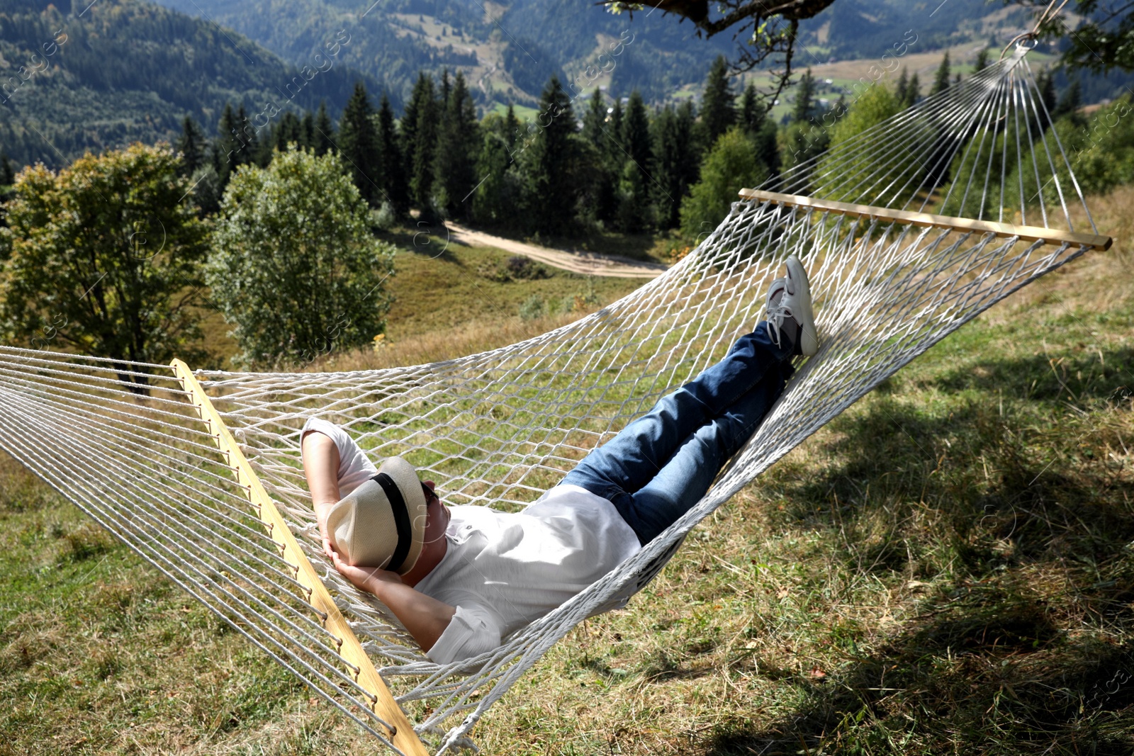 Photo of Young man resting in hammock outdoors on sunny day