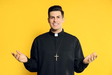 Photo of Priest wearing cassock with clerical collar on yellow background