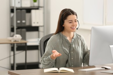 Photo of Hotline operator with headset working on computer in office. Space for text