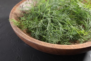 Photo of Bowl of fresh dill on grey textured table, closeup