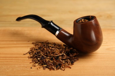 Photo of Smoking pipe with tobacco on wooden table