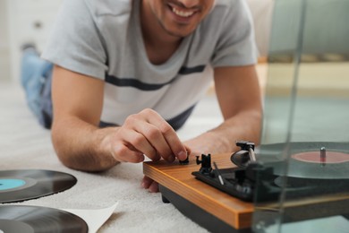 Happy man using turntable at home, closeup