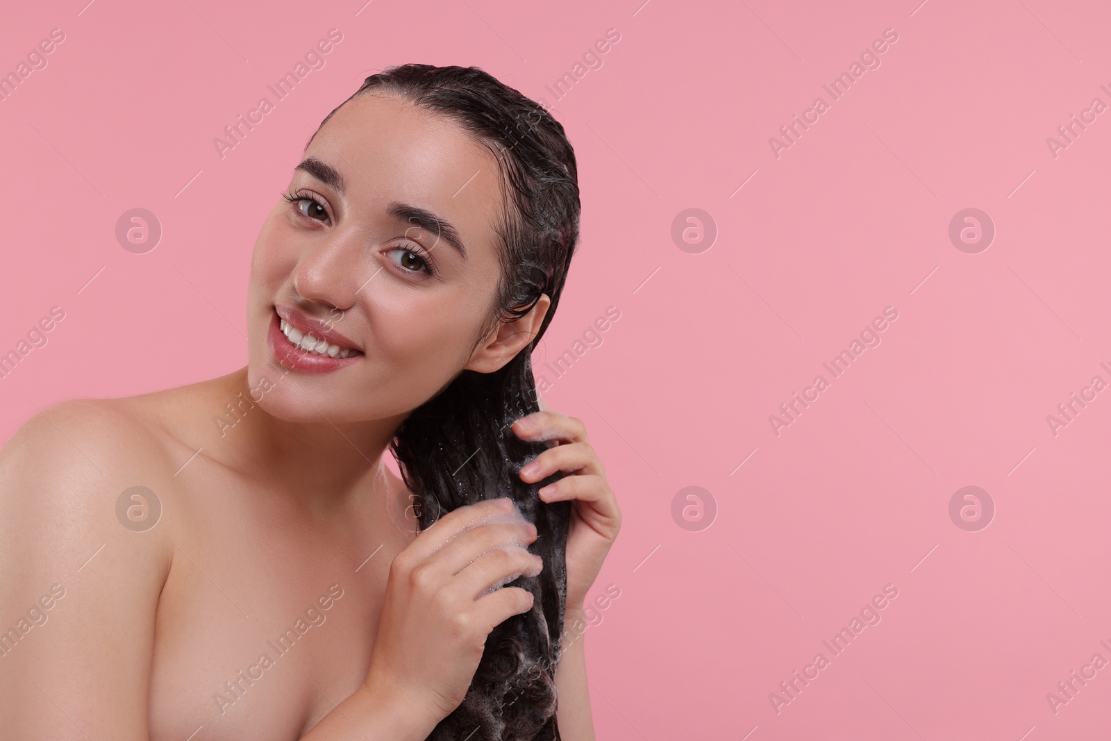 Photo of Beautiful happy woman washing hair on pink background. Space for text