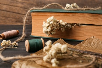 Book with flowers as bookmark on wooden table, closeup