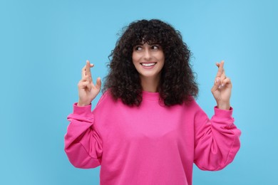Photo of Woman crossing her fingers on light blue background