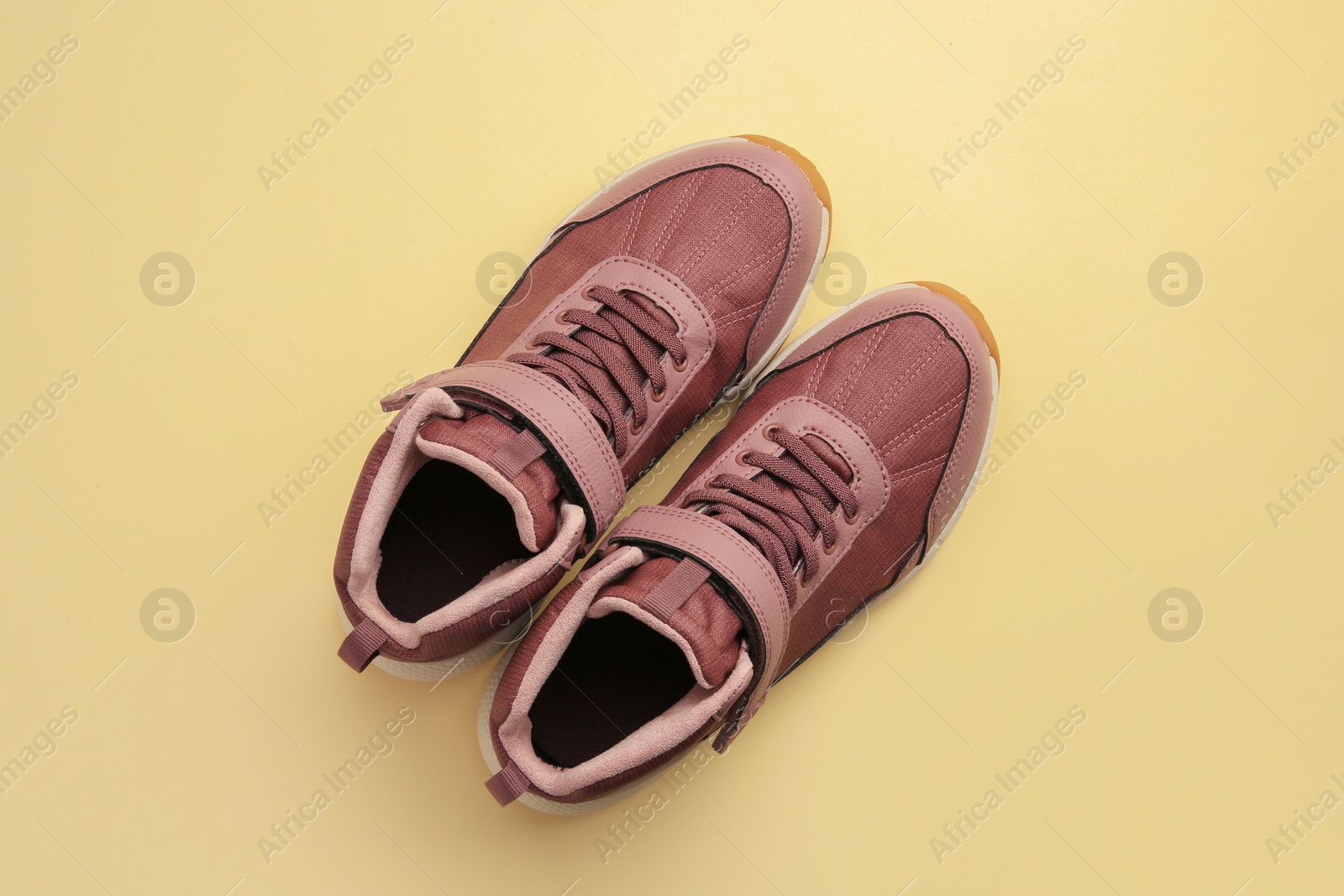 Photo of Pair of stylish kid's sneakers on beige background, top view