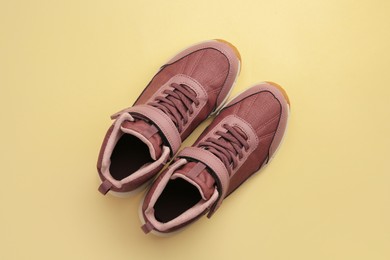 Pair of stylish kid's sneakers on beige background, top view