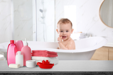 Baby cosmetic products, toy and towels on table in bathroom
