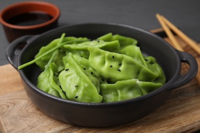 Photo of Delicious green dumplings (gyozas) and soy sauce on grey table, closeup