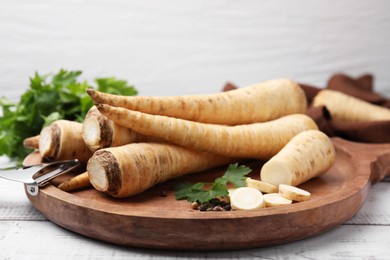 Raw parsley roots and fresh herb on white wooden table, closeup