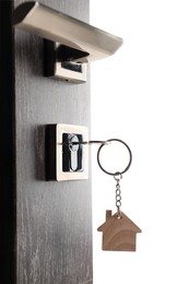 Photo of Mortgage and real estate. Open door with key and house shaped keychain on white background