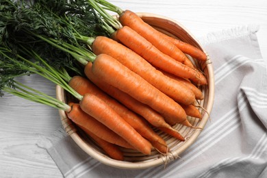 Many tasty ripe carrots on white wooden table, top view