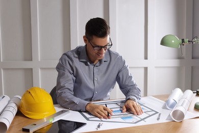 Photo of Architect working with construction drawings in office