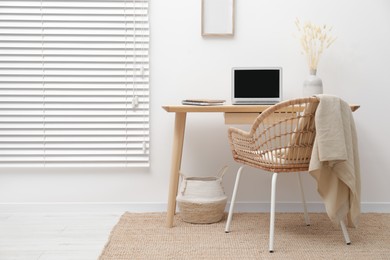 Photo of Cozy workspace with modern laptop on desk and comfortable chair at home