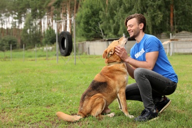 Male volunteer with homeless dog at animal shelter outdoors