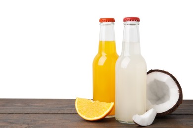 Delicious kombucha in glass bottles, orange and coconut on wooden table against white background, space for text