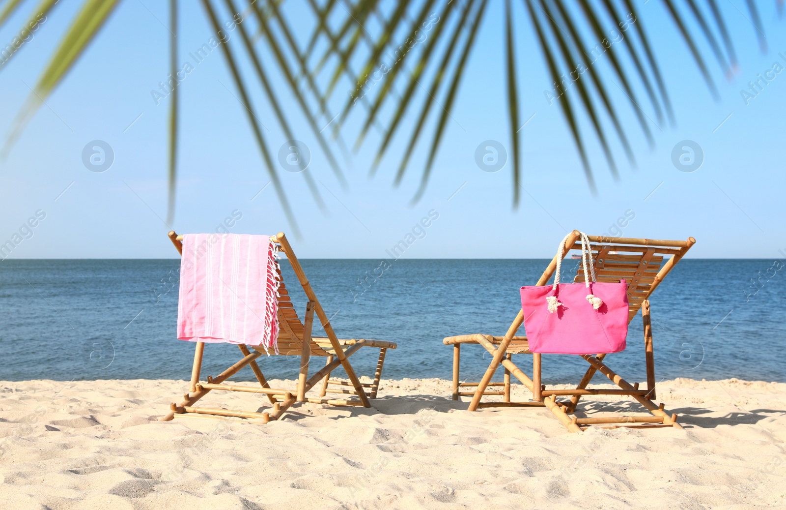 Photo of Empty wooden sunbeds and beach accessories on sandy shore