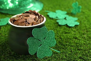 Photo of Pot of gold coins and clover on green grass, closeup. St. Patrick's Day celebration